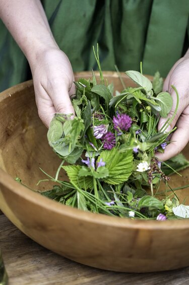 Woman holding various flowers in a bowl in her hand. | © Florian Bachmeier