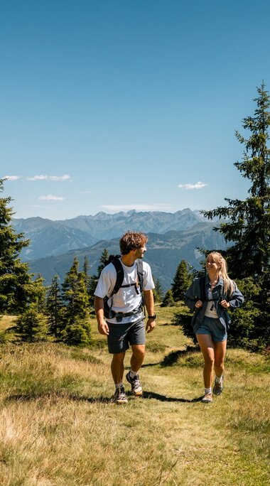 Zwei Wanderer auf einem Wiesenweg bei Piesendorf mit Blick auf die Hohen Tauern. | © Ferienregion Nationalpark Hohe Tauern - Mathäus Gartner