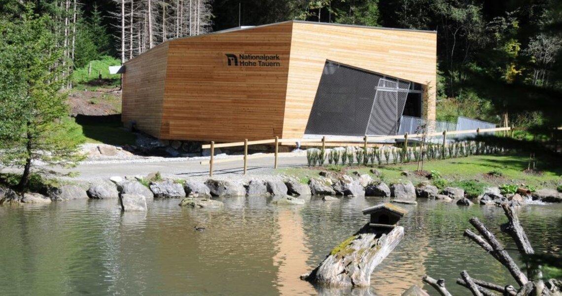 Holzgebäude der Nationalparkausstellung „Leben unter Wasser“ an einem idyllischen Teich. | © Wild- und Erlebnispark Fusch/Ferleiten