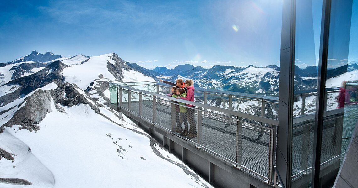Familie auf der Nationalpark-Panoramaplattform mit Blick auf verschneite Berggipfel. | © Kitzsteinhorn Talstation