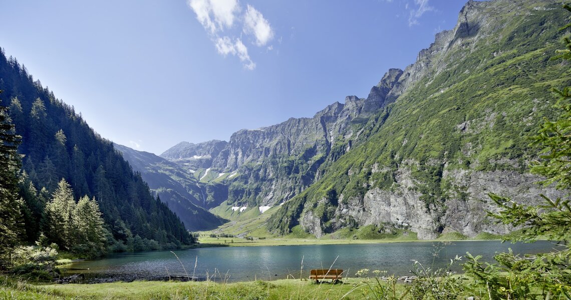 Malerischer Bergsee mit klar blauem Wasser und steilen, bewaldeten Felswänden im Hintergrund. | © Ferienregion Nationalpark Hohe Tauern