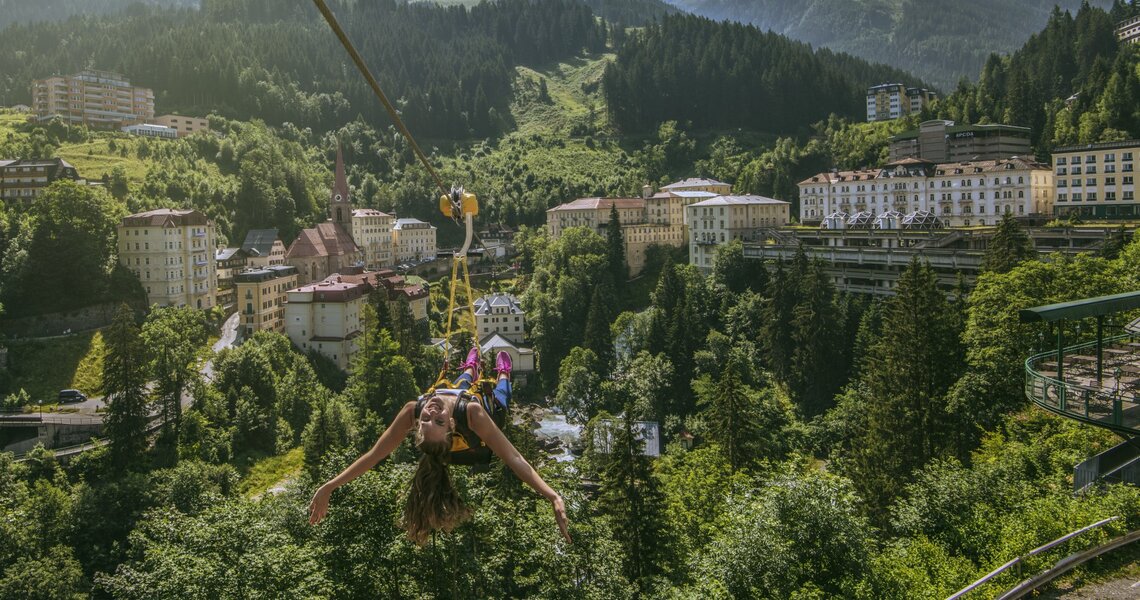 Frau gleitet an einer Zipline über die malerische Kulisse von Bad Gastein mit Bergen im Hintergrund. | © Tourismusverband Bad Gastein
