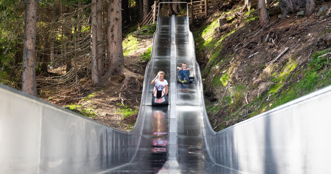 Children sliding on a stainless steel slide in the forest. | © Wildkogel-Arena Neukirchen & Bramberg
