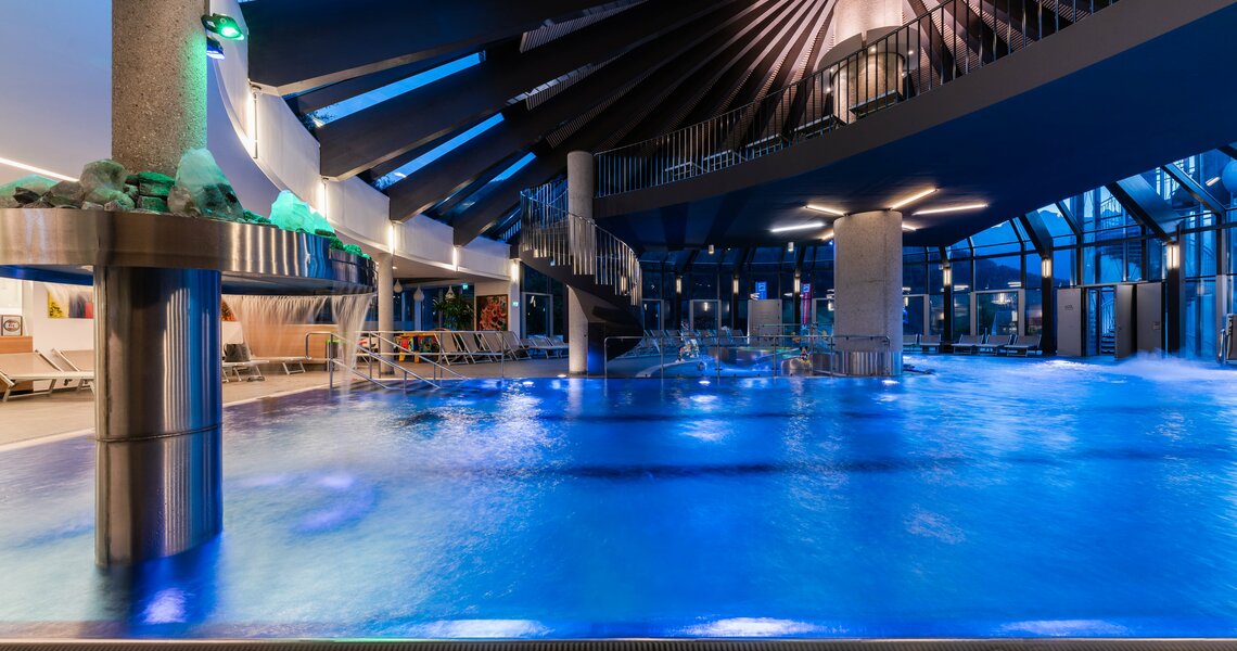 Interior view of the illuminated Kristallbad Wald with pool and loungers. | © © Kristallbad Wald Königsleiten GmbH