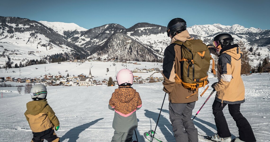 Familie auf Skiern genießt den Ausblick auf Embach im Schnee. | © ©sobietzki