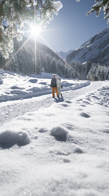 Winterwanderer auf sonnigem Schneepfad durch verschneite Berglandschaft. | © Ferienregion Nationalpark Hohe Tauern - Daniel Breuer