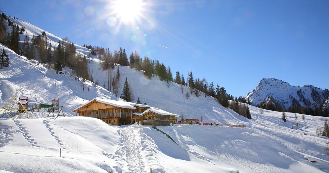 Sonnige Winterlandschaft mit Hütte im Schnee in den Bergen.