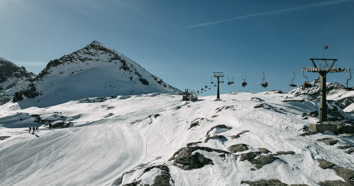  Chairlift over snowy ski area with rocks and mountain backdrop in bright sunshine. | © TVB Uttendorf - Klaus Steiner