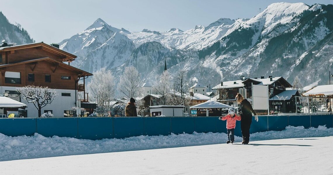 Kind lernt Schlittschuhlaufen auf Eisbahn mit Bergkulisse im Hintergrund. | © Zell am See Kaprun