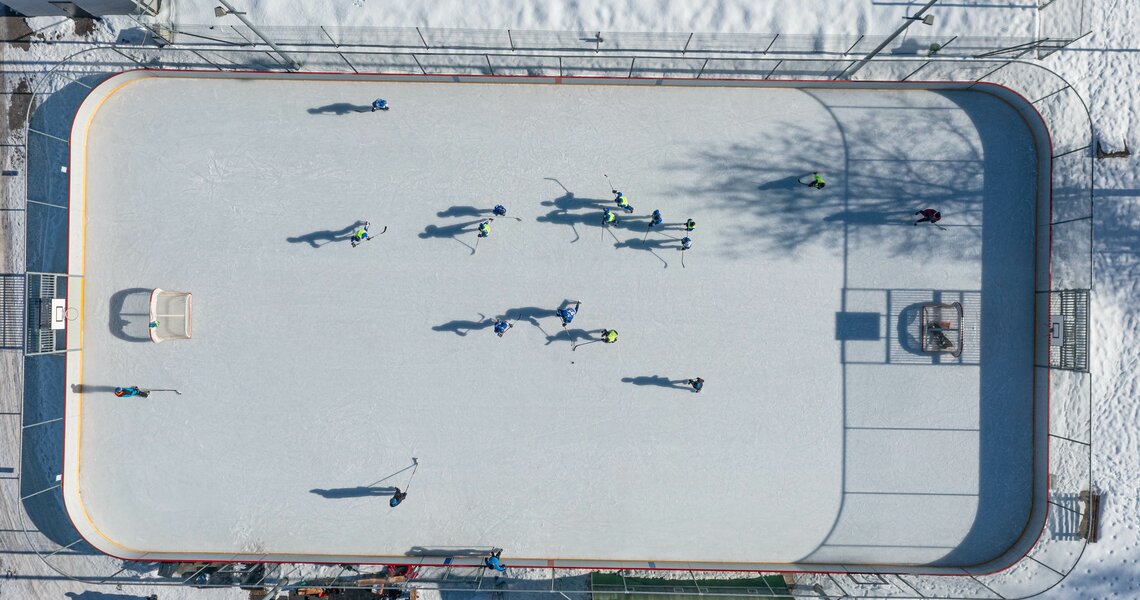Aerial view of an ice hockey game on a snowy outdoor rink. | © Gerry Lobenwein