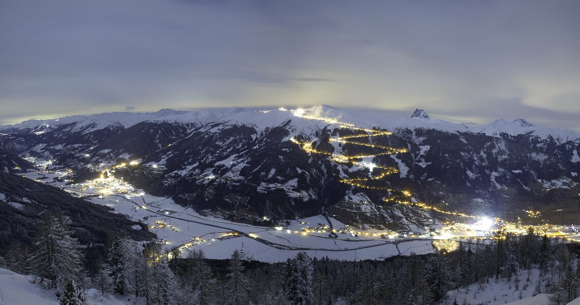 Winter mountain landscape with illuminated ski slope at night.