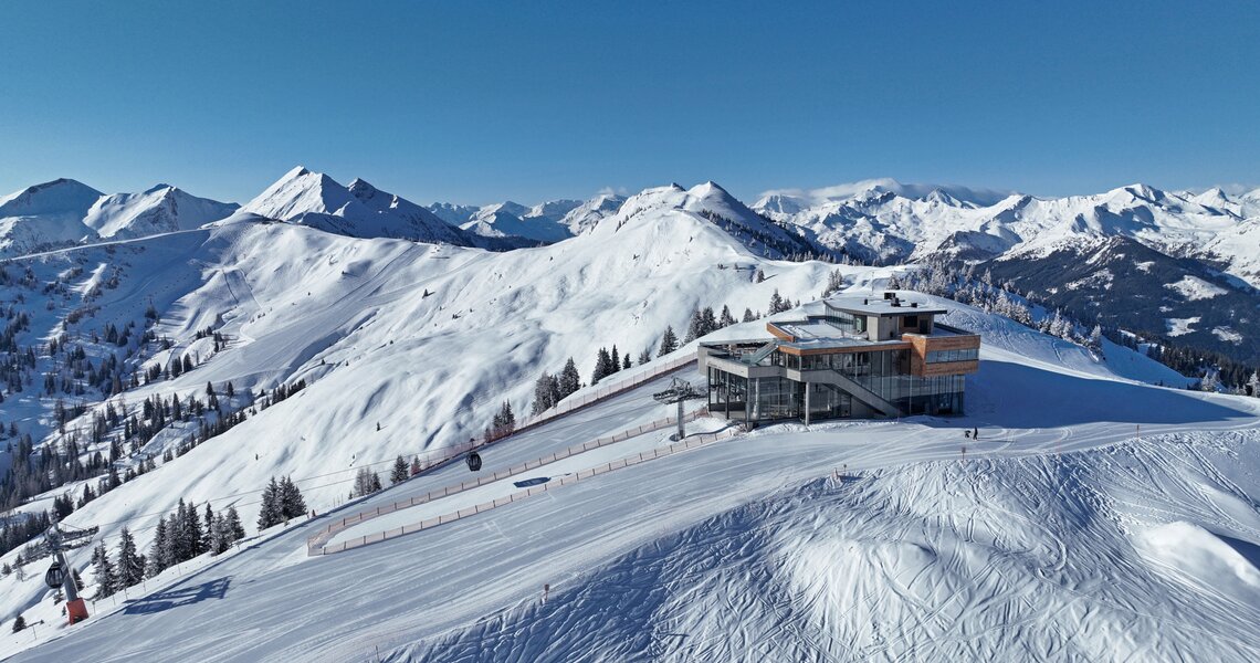 Panoramablick auf moderne Bergstation in verschneiter Alpenlandschaft bei blauem Himmel. | © TVB Großarltal