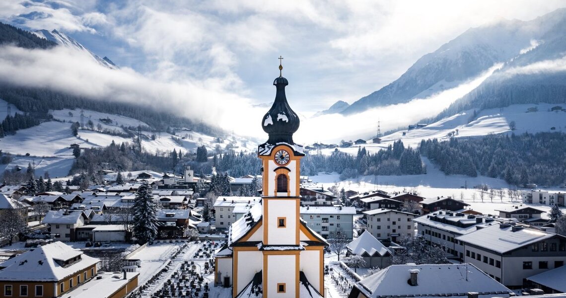 Verschneiter Ortskern mit Kirche vor alpiner Winterlandschaft im Nationalpark Hohe Tauern | © Kogler Daniel