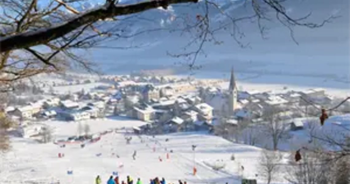 Ski group in front of snowy alpine village with church | © Hohe Tauern National Park holiday region